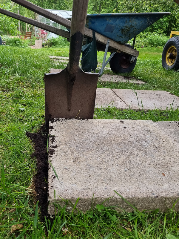 steg 1 när du lägger stegstenar i gräsmattan är att lägga ut stenarna och skära runt med en vass spade